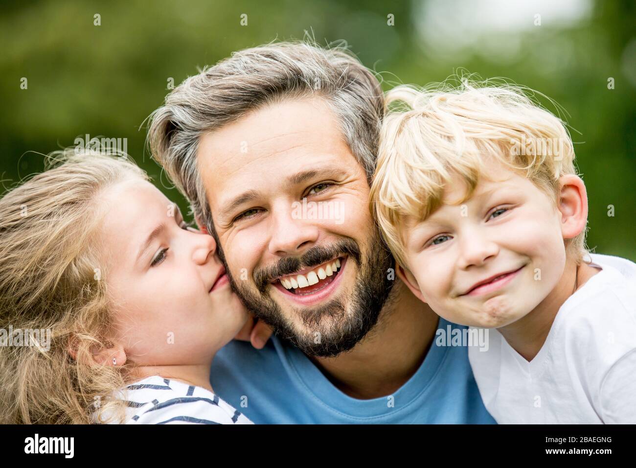 Buon padre con due bambini ride in giardino in estate Foto Stock