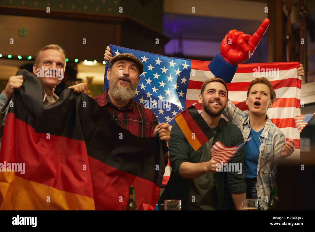 Gruppo di tifosi tedeschi e americani che si rallegrano per le loro squadre di calcio nello sport bar Foto Stock