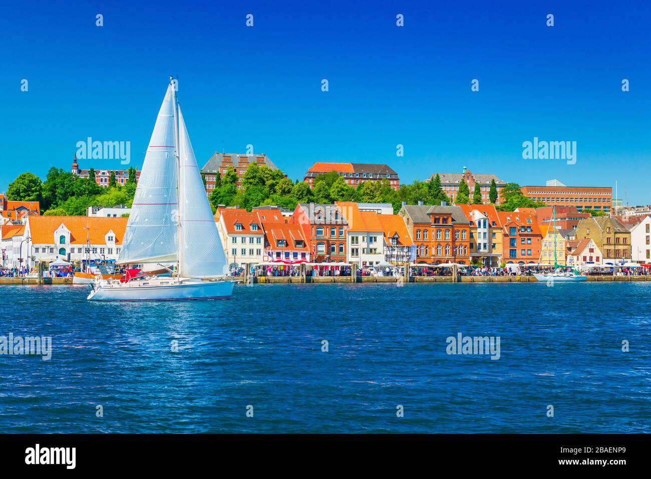 Bellissimo panorama di una città portuale europea. Uno yacht naviga contro lo skyline della città di Flensburg, Germania Foto Stock