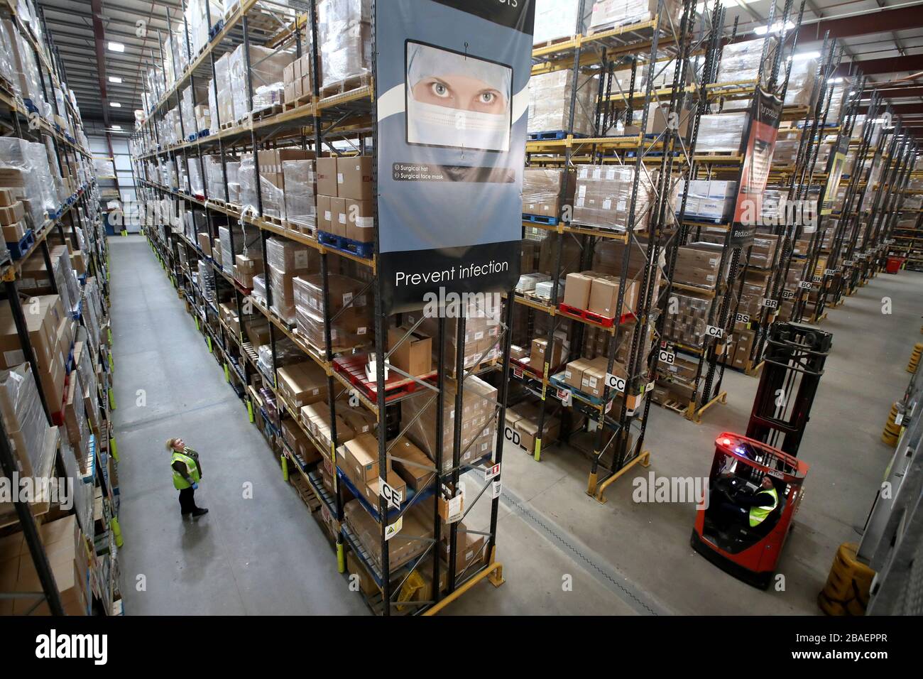 I lavoratori del magazzino raccolgono i rifornimenti presso il National Procurement Warehouse di Canderside, Larkhall, mentre le consegne di dispositivi di protezione individuale (PPE) sono in aumento, con milioni di maschere e guanti già consegnati al personale in prima linea. Foto Stock