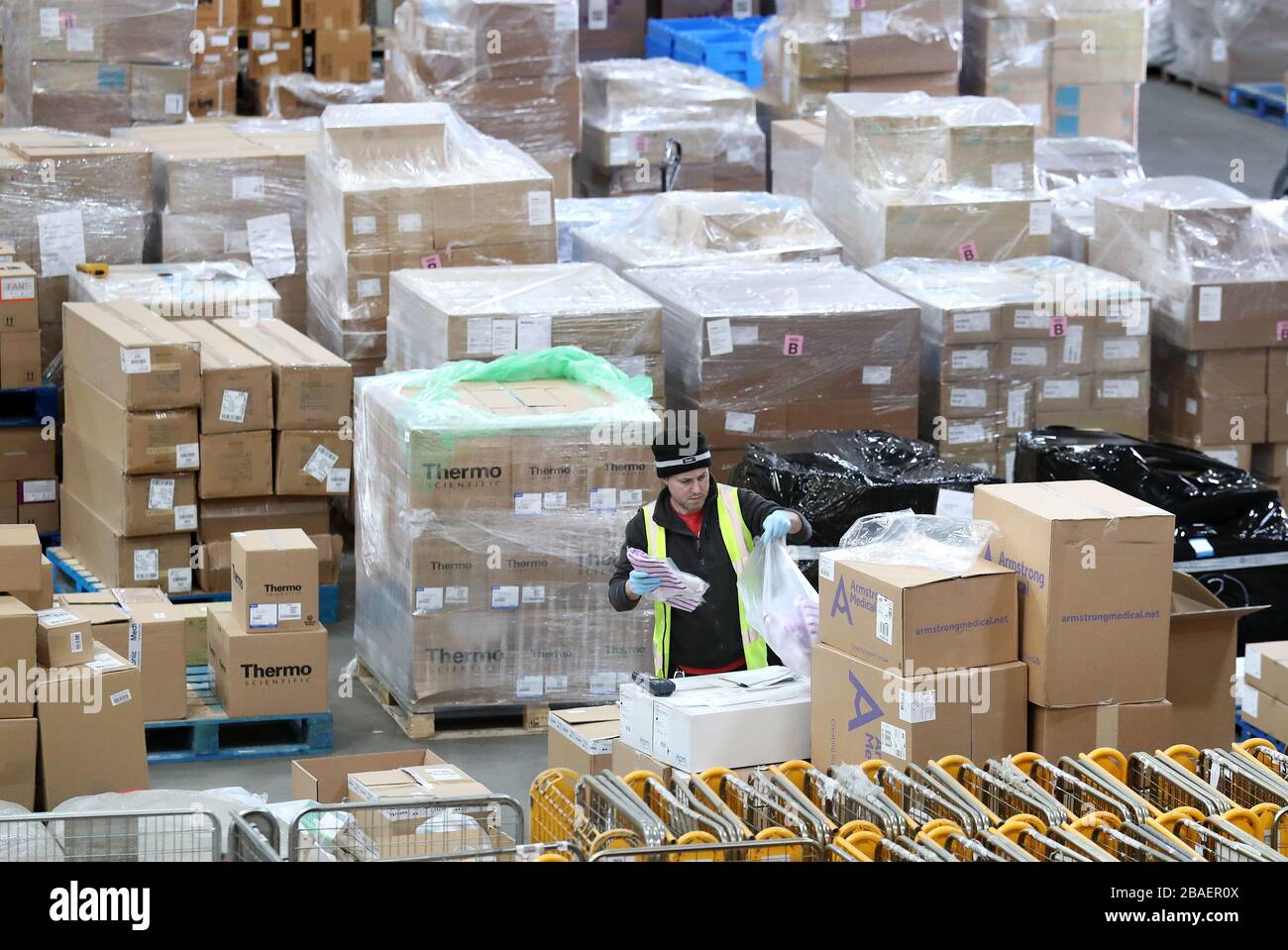Un lavoratore raccoglie le forniture presso il National Procurement Warehouse di Canderside, Larkhall, mentre le consegne di dispositivi di protezione individuale (PPE) sono in aumento, con milioni di maschere e guanti già consegnati al personale di prima linea. Foto Stock