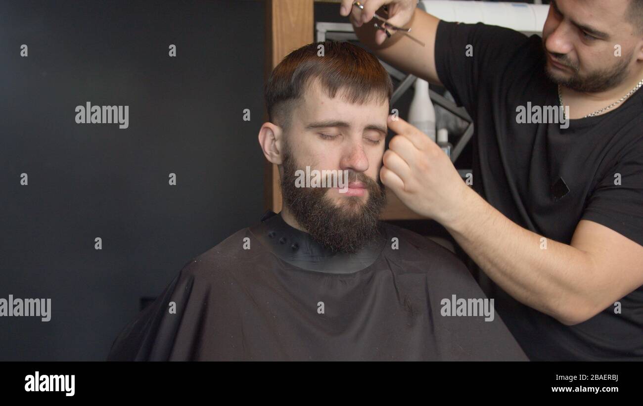 Giovane barbiere taglio capelli del cliente maschio Foto Stock