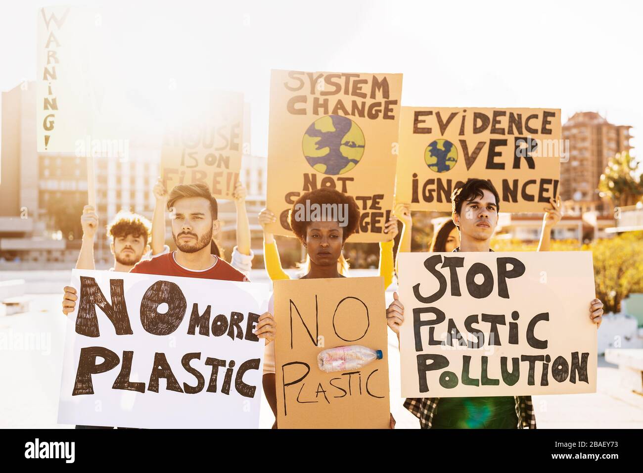 Manifestanti di gruppo che protestano contro l'inquinamento della plastica e il cambiamento climatico - persone Multirazziali che lottano su strada con striscioni Foto Stock