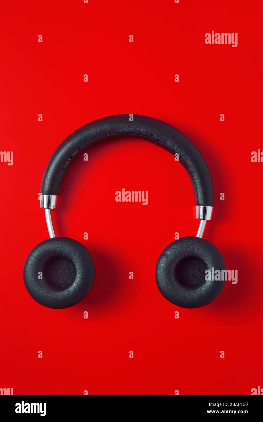 visualizzazione ad alta angolazione di un paio di cuffie wireless di dimensioni normali nere su sfondo rosso Foto Stock