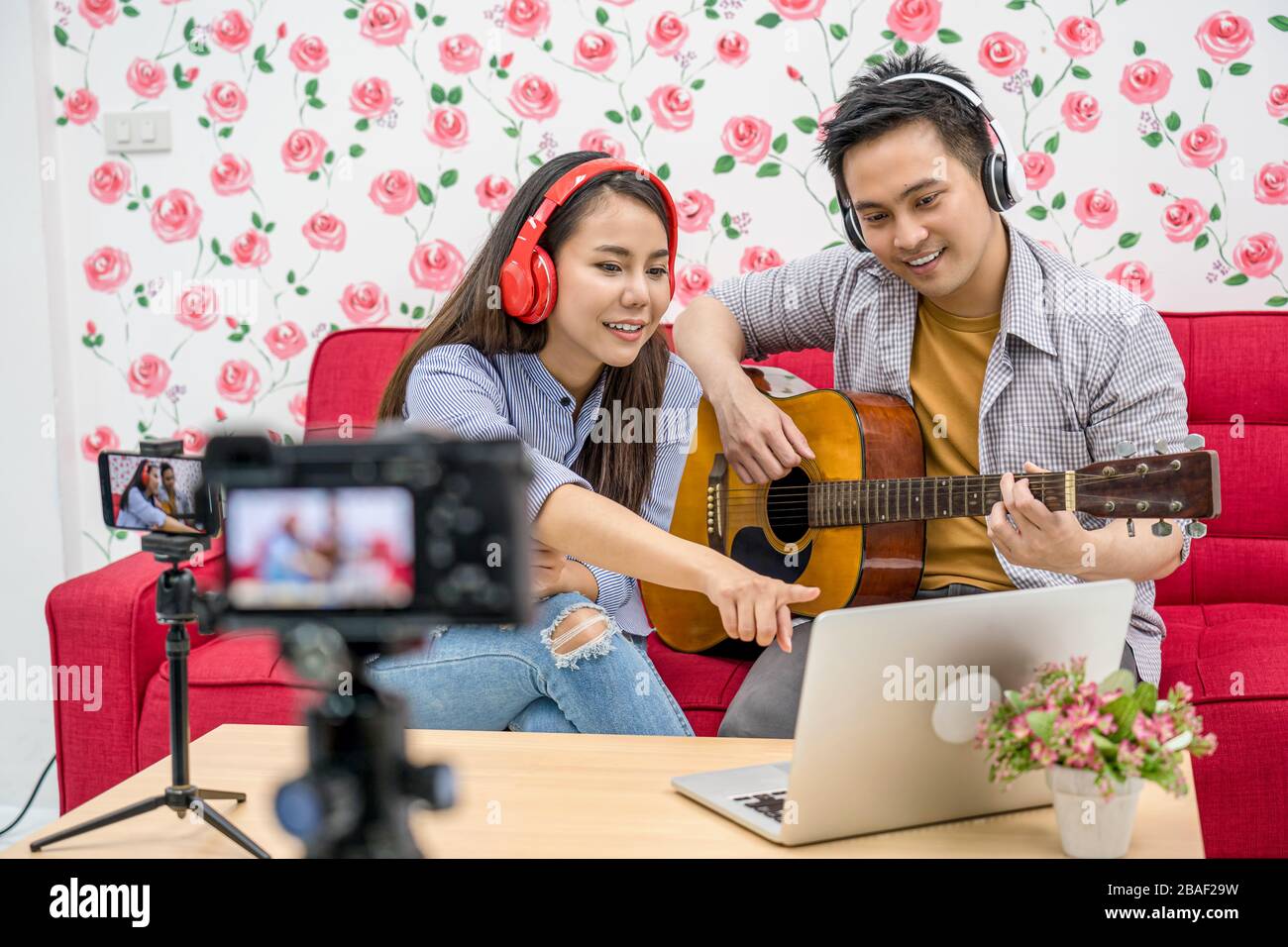 Asian Vlogger di coppia sposata che gioca e condivide la musica ai partecipanti via telefono cellulare dal canale dei social media, controllando il commento via laptop, fotocamera Foto Stock Asian Vlogger di coppia sposata che gioca e condivide la musica ai partecipanti via telefono cellulare dal canale dei social media, controllando il commento via laptop, fotocamera Foto Stock
