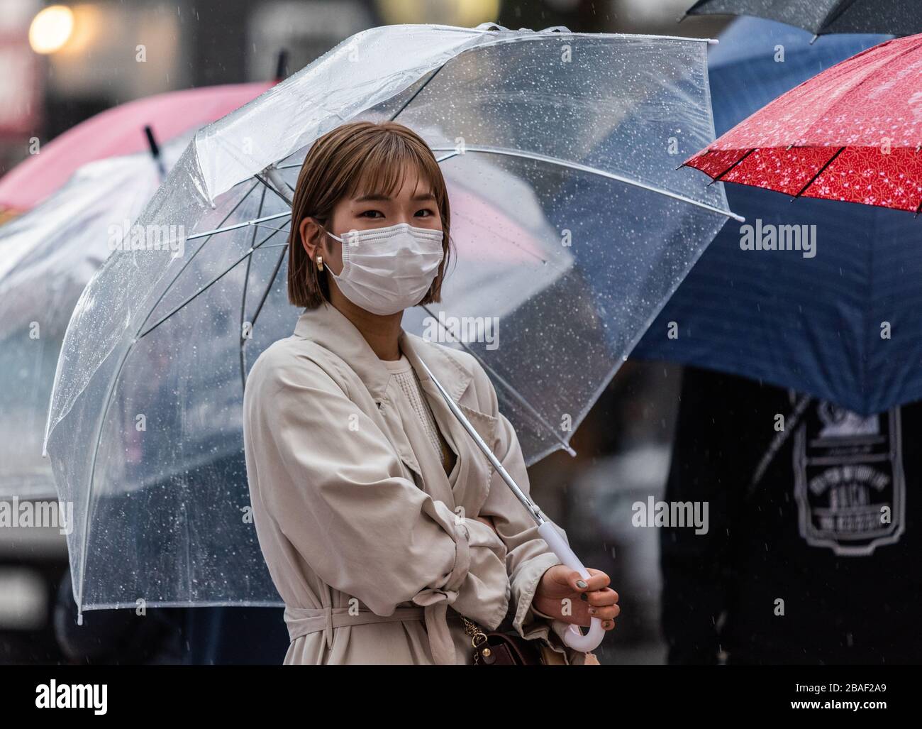 Tokyo, Giappone – 10 marzo 2020. Donna che indossa una maschera sulla scia della pandemia di coronavirus globale, in una giornata piovosa a Tokyo. Foto Stock