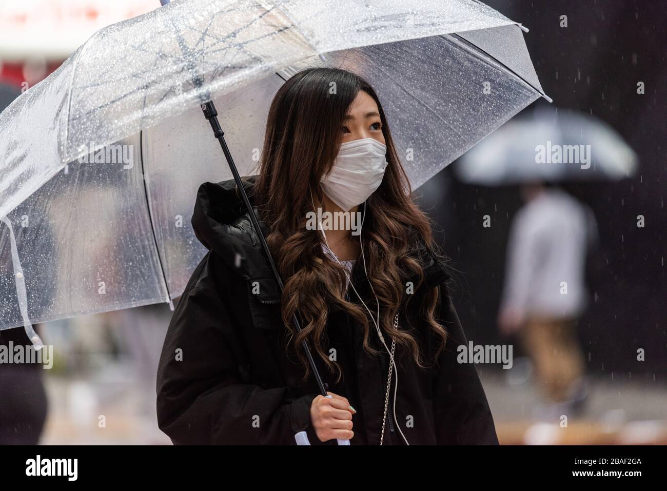 Tokyo, Giappone – 10 marzo 2020. Donna che indossa una maschera sulla scia della pandemia di coronavirus globale, in una giornata piovosa a Tokyo. Foto Stock