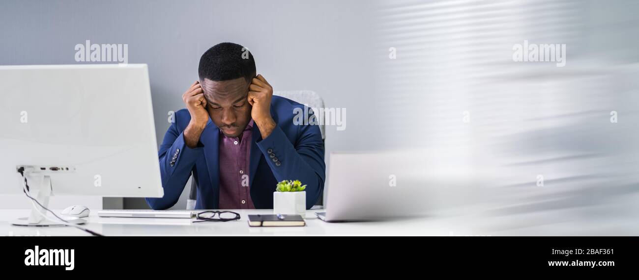 Un giovane uomo d'affari preoccupato che guarda il computer alla scrivania dell'ufficio Foto Stock