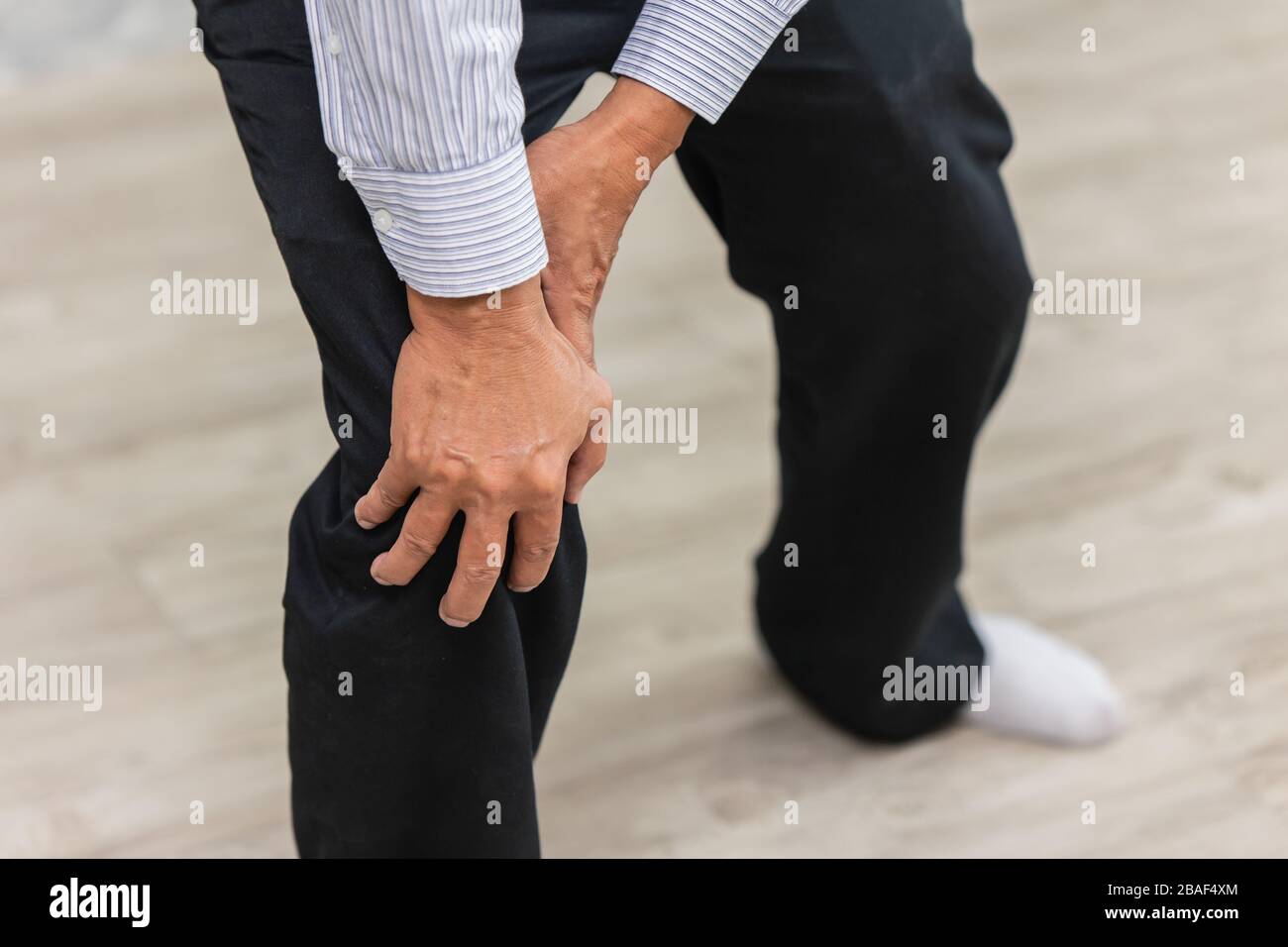mano di closeup che tiene dolore al ginocchio uomo anziano. Foto Stock