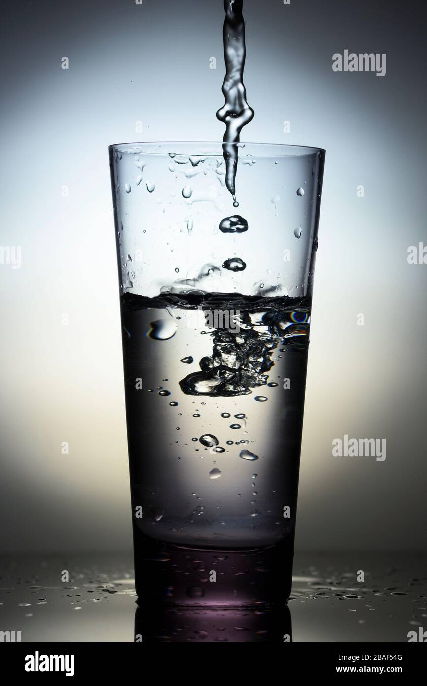 Bere acqua che si versa nel bicchiere . Primo piano. Scatto verticale Foto Stock