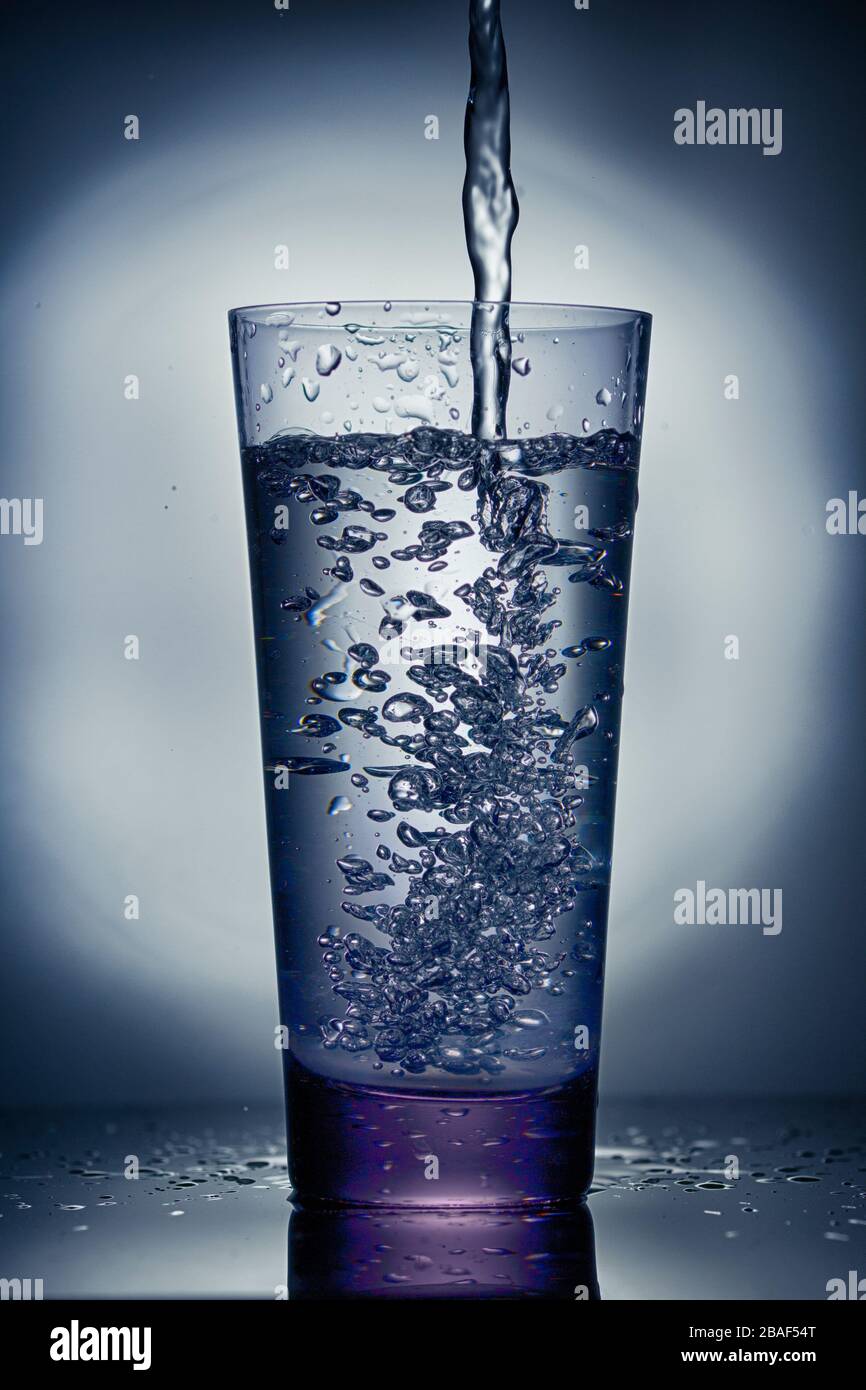 Versare acqua in un bicchiere. Chiudere . Tonato Foto Stock