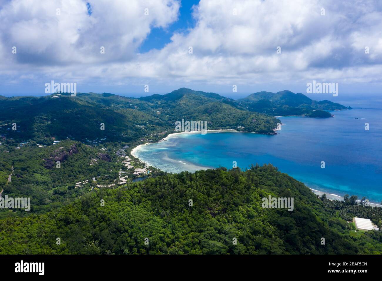Vista panoramica aerea con drone sulla costa dell'isola di Mahe con lussureggianti montagne verdi, baia, spiaggia e Oceano Indiano, Seychelles Foto Stock