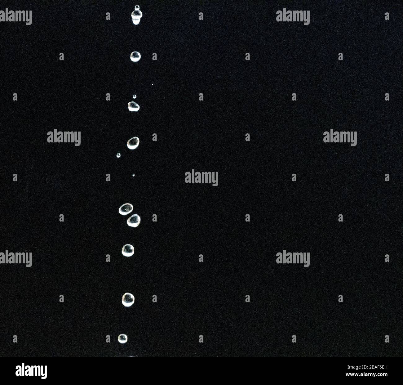 gocce d'acqua che cadono contro una goccia di fondo nera Foto Stock