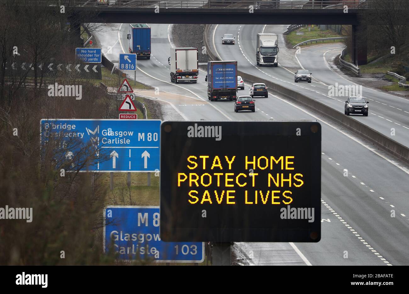 Un cartello stradale che consiglia ai conducenti di rimanere a casa Protect NHS salva vite è visibile sulla M80 vicino a Banknock, mentre il Regno Unito continua in blocco per contribuire a frenare la diffusione del coronavirus. Foto Stock