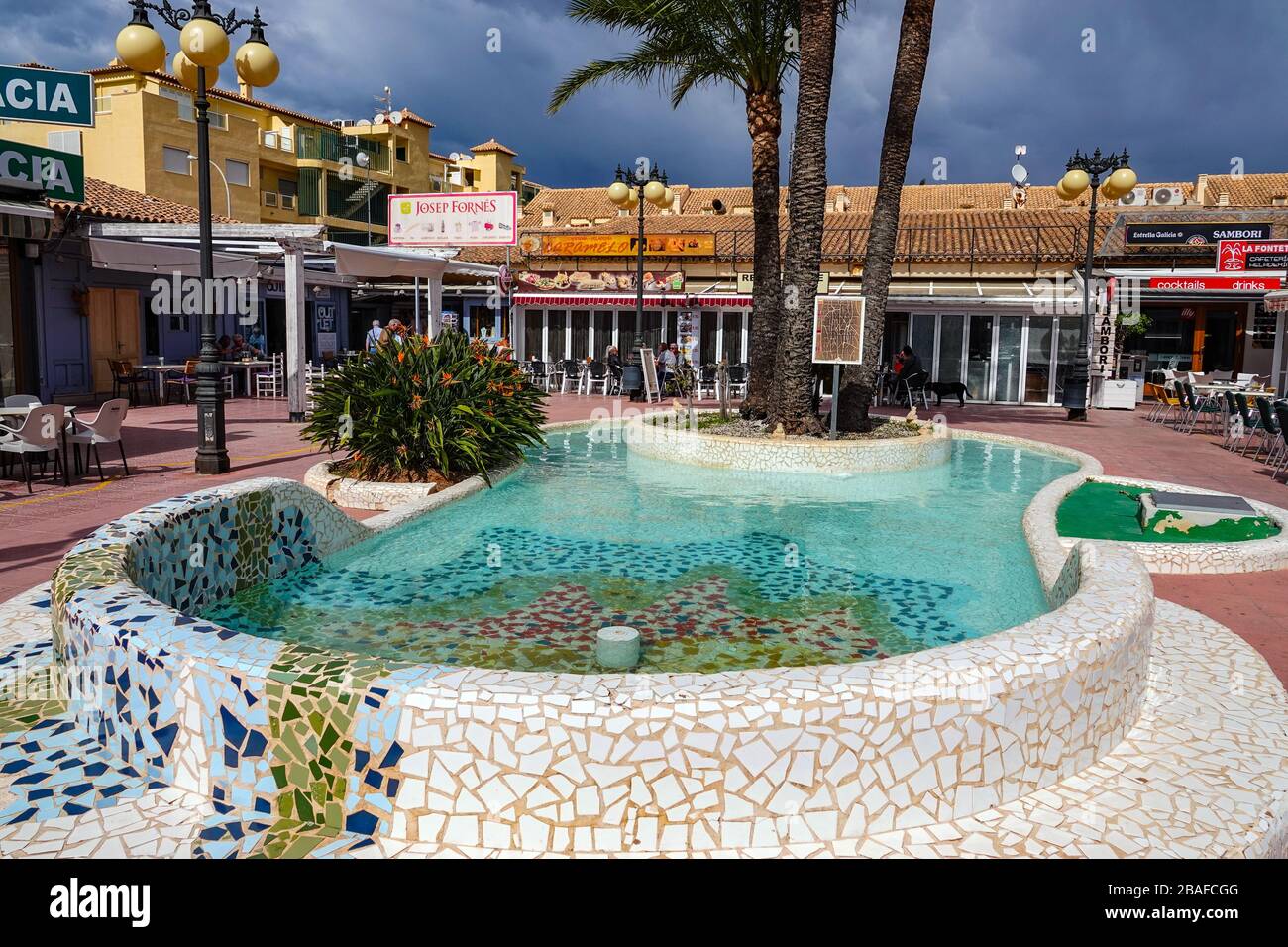 Fontana in stile Guadi e palme, con caffè, la città di Denia, Alicante, Costa Blanca, Spagna Foto Stock
