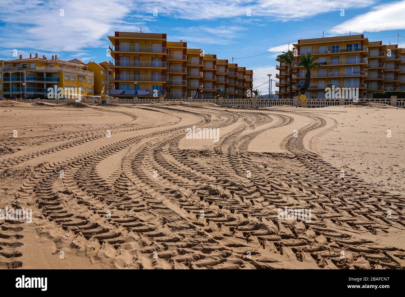 Trattori su ampia spiaggia di sabbia deserta con blocchi di appartamenti a Denia, Costa Blanca, Spagna Foto Stock
