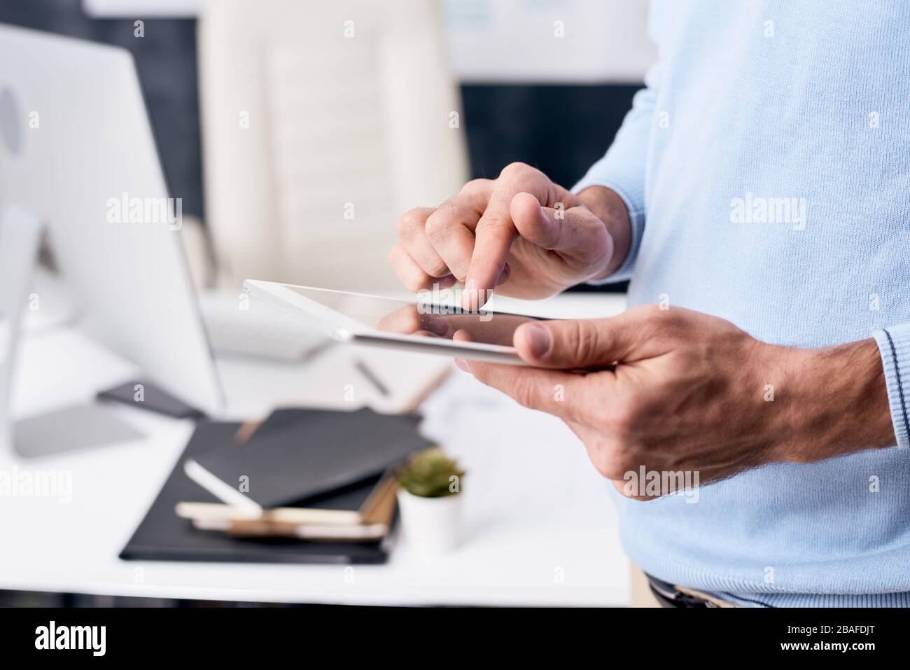 Primo piano di un uomo irriconoscibile che controlla le e-mail sul tablet in attesa di una proposta aziendale da parte del partner aziendale Foto Stock
