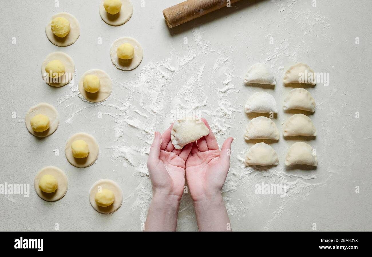 Donna mani sculture gnocchi con patate su sfondo bianco. Cibo ucraino tradizionale. Foto Stock