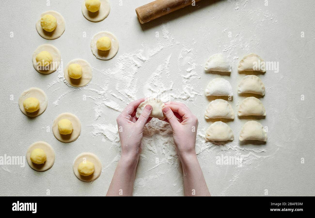 Donna mani sculture gnocchi con patate su sfondo bianco. Cibo ucraino tradizionale. Foto Stock