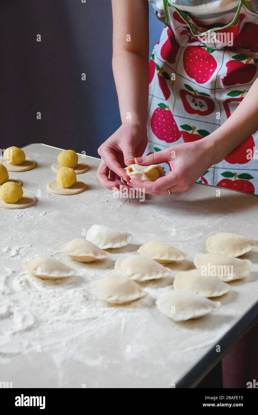 Donna mani sculture gnocchi con patate su sfondo bianco. Cibo ucraino tradizionale. Foto Stock