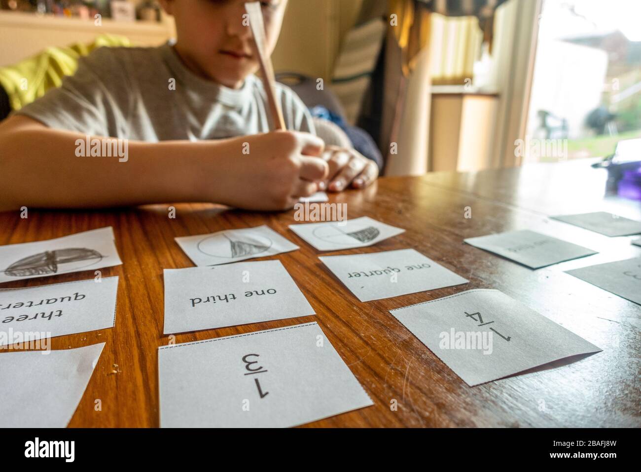 Un ragazzo sta imparando circa le frazioni a casa facendo i compiti di matematica che è stato inviato durante la pandemia di coronavirus. Foto Stock