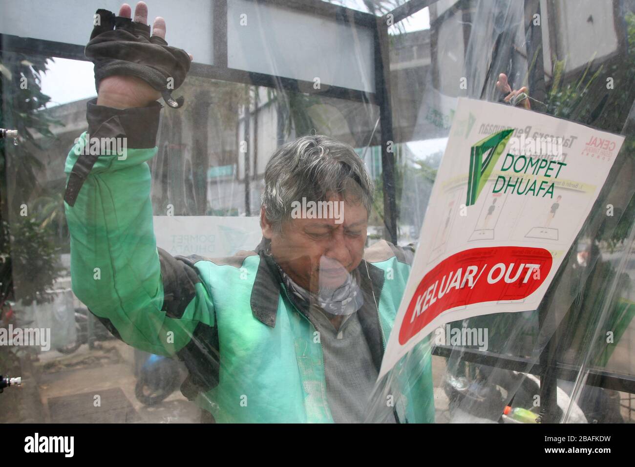 I residenti che saranno attivi in luoghi pubblici, utilizzano la camera di disinfezione di Blok M, South Jakarta, Indonesia il 25 marzo 2020. In questa camera di sterilizzazione tutto il corpo della persona verrà spruzzato con liquido disinfettante. Questo liquido disinfettante ha la funzione di uccidere il virus della corona che si attacca ai vestiti o al corpo della persona, per anticipare la diffusione del virus della corona (COVID-19) negli spazi pubblici. (Foto di Kuncoro Widyo Rumpoko/Pacific Press/Sipa USA) Foto Stock