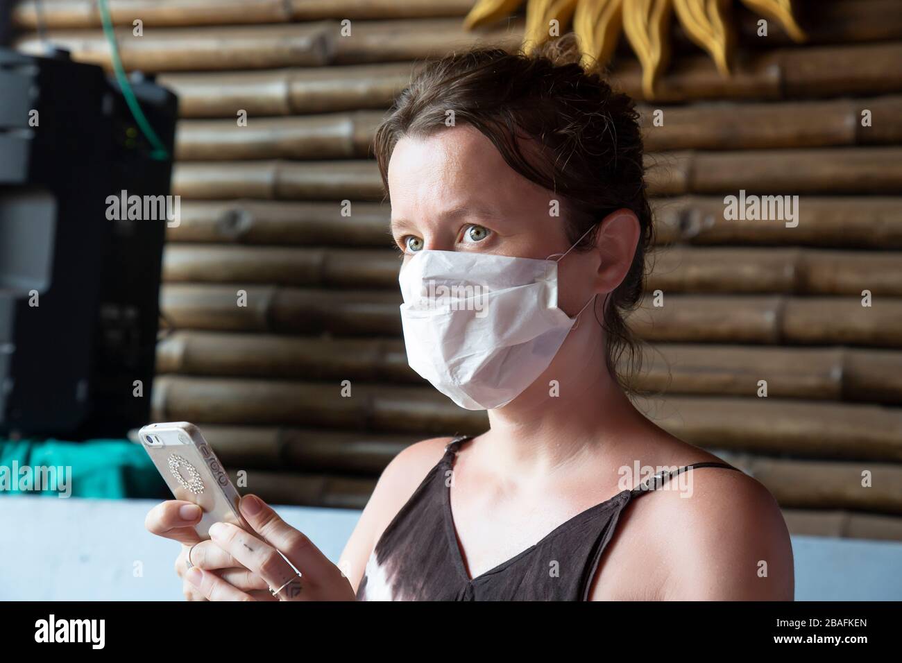 Turismo femminile caucasico con maschera facciale in India con il suo cellulare appena realizzato, che il suo volo è stato annullato Foto Stock