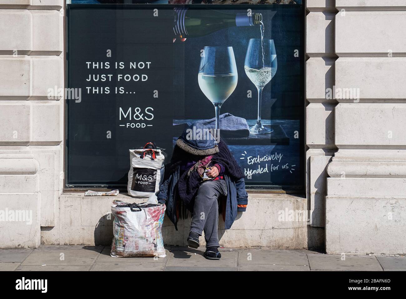Un uomo senza tetto si trova al di fuori di un Marks and Spencer a Mayfair, Londra, come il governo ha chiesto alle autorità locali in Inghilterra di ospitare tutti i dormitori e quelli in ostelli e rifugi notturni entro il fine settimana, la crisi di carità ha detto. Foto Stock