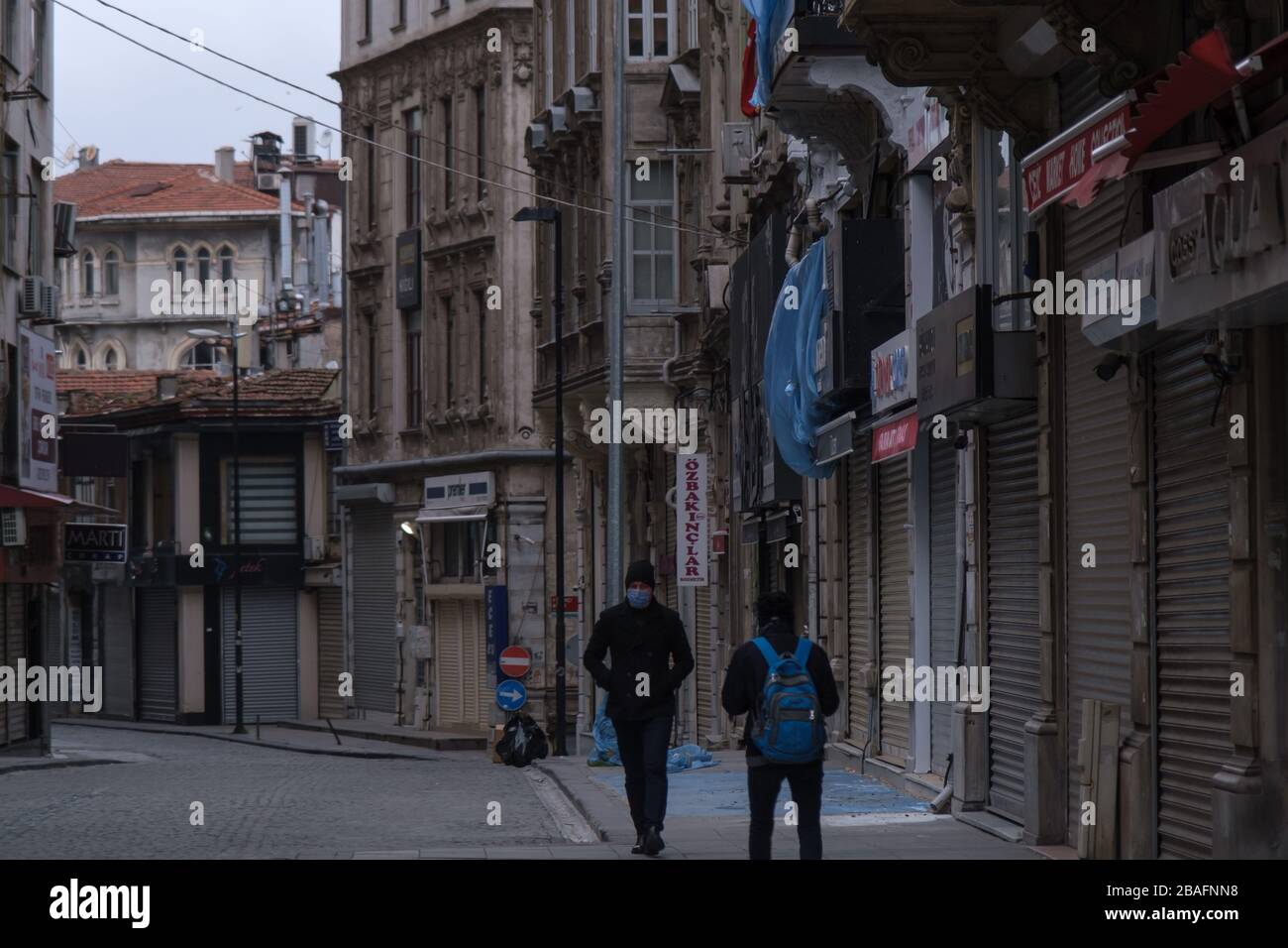 Giovane turco che indossa maschera facciale per proteggere dal virus Corona (COVID-19) camminando nelle strade vuote. Sembra che tutti i negozi siano chiusi nelle vicinanze. Foto Stock