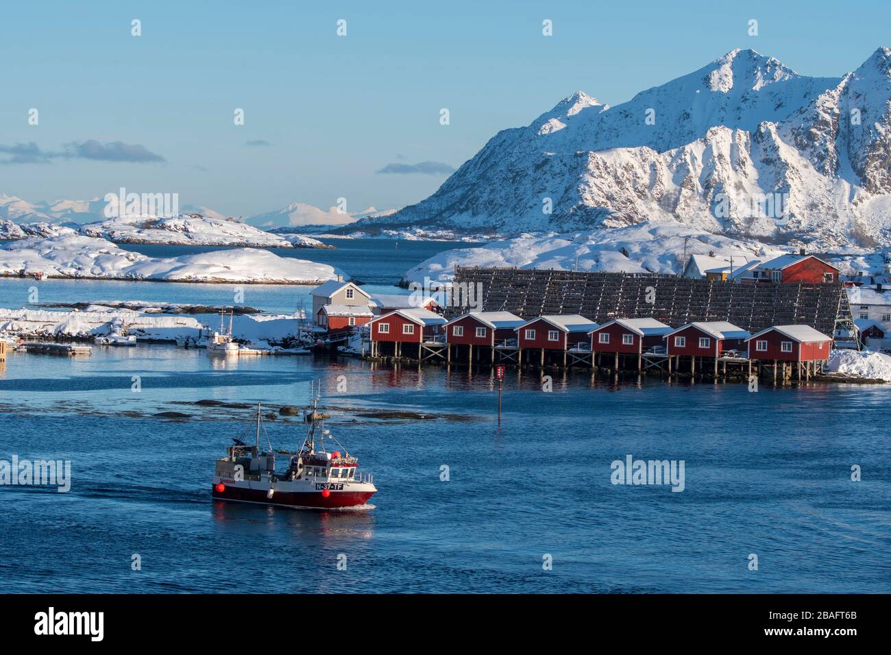 Una barca da pesca passa davanti ai cottage di pesca presso il Svinoeya Rorbuer (hotel) a Svolvaer, una città di pescatori nelle isole Lofoten, Nordlan Foto Stock
