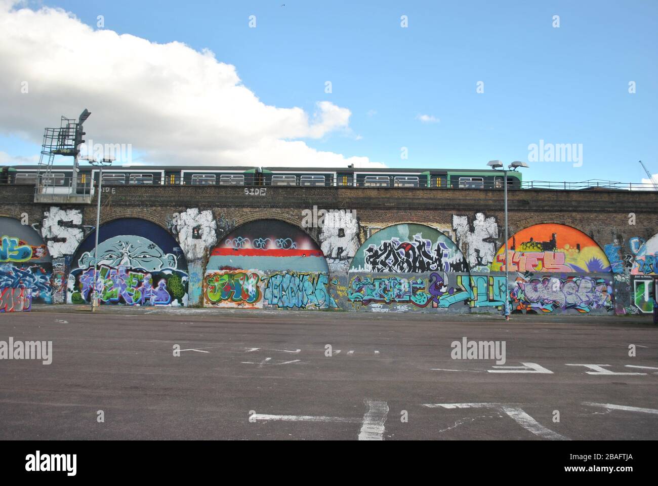 ARCHI FERROVIARI DI PECKHAM COPERTI DI GRAFFITI CON UN TRENO FERROVIARIO MERIDIONALE CHE PASSA SOPRA. Foto Stock