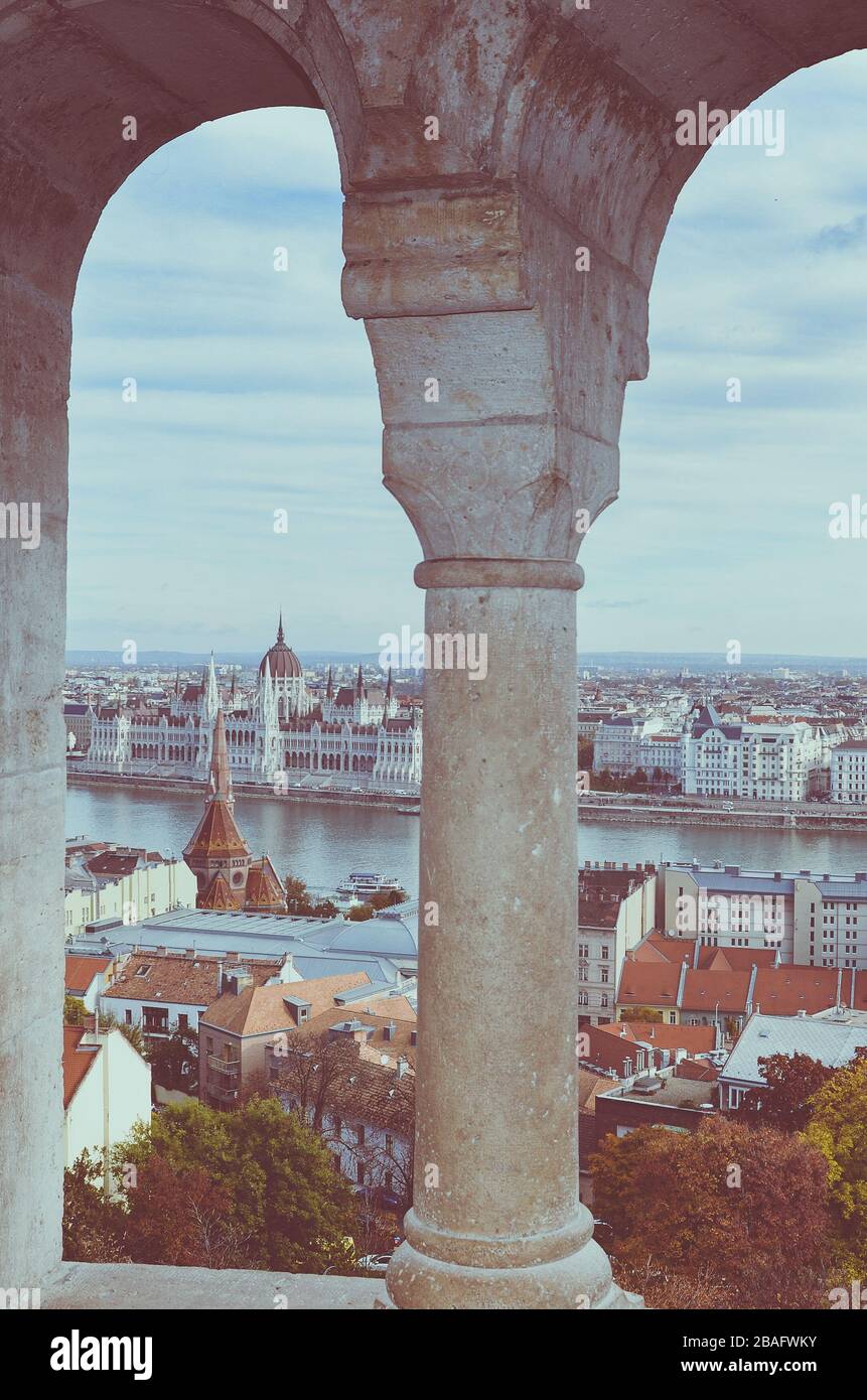 Paesaggio urbano di Budapest, Ungheria fotografato attraverso la finestra dell'arco del Bastione dei pescatori. Palazzo del Parlamento ungherese, Orszaghaz, sullo sfondo dell'altro lato del Danubio. Foto Stock