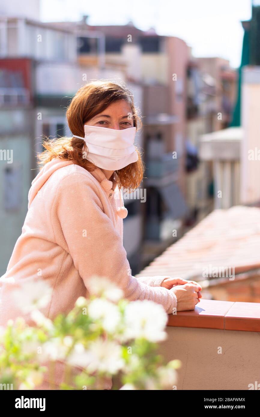 Donna con maschera confinata in casa prendendo aria sulla terrazza, misure contro Coronavirus, COVID 19 Foto Stock