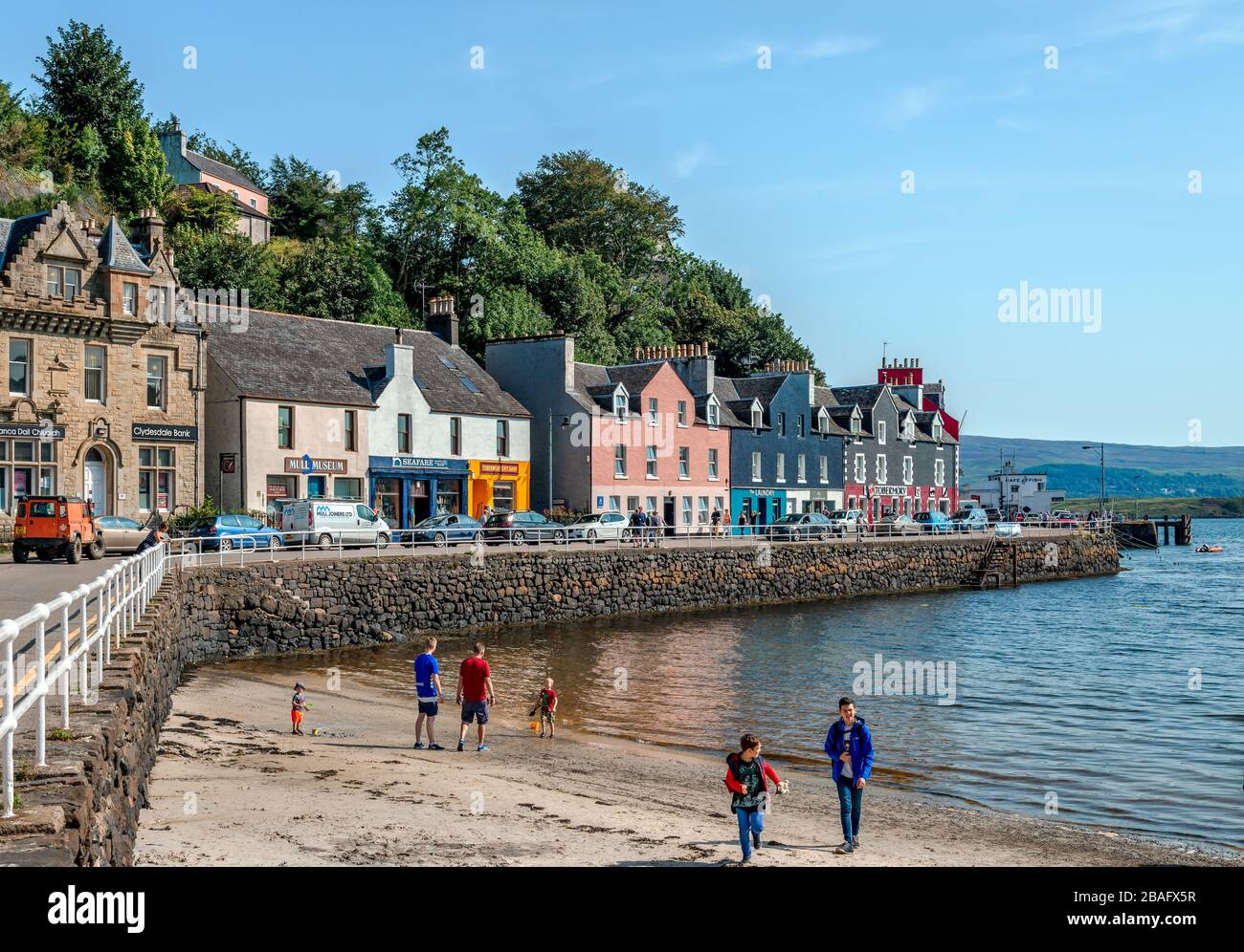 Tobermory / UK - 25 agosto 2019: Vista sul lungomare. La gente gode la mattina soleggiata in spiaggia, vicino al mare. Foto Stock