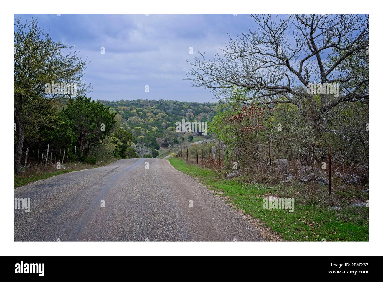Texas Hill Country strada rurale con colline e un cielo nuvoloso Foto Stock