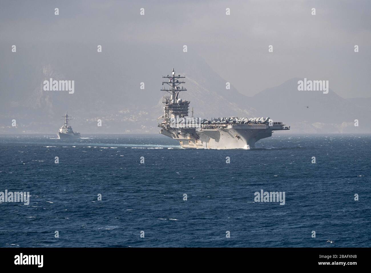 La US Navy Nimitz-classe vettore aereo USS Dwight D. Eisenhower in formazione con la Arleigh Burke-classe guidato-missile cacciatorpediniere USS James E. Williams transita lo stretto di Gibilterra 29 febbraio 2020 nel Mar Mediterraneo. Foto Stock