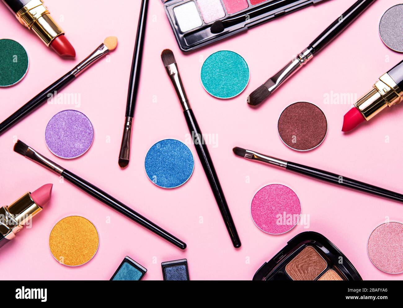 Diversi pennelli per il trucco e eye shadow sul rosa pastello sfondo. Appartamento laico, vista dall'alto. Foto Stock