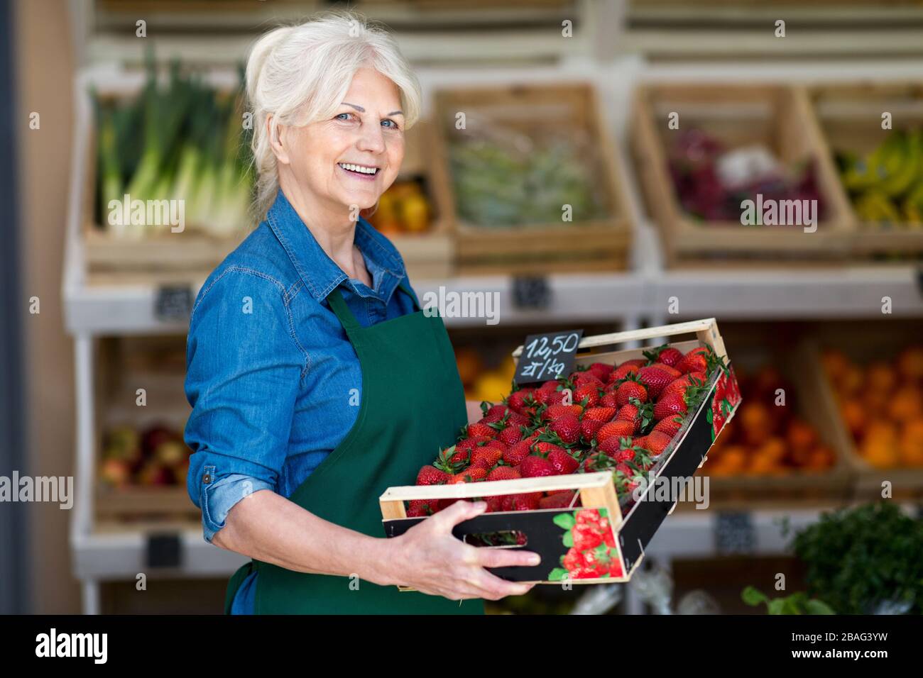 Donna senior che lavora in un piccolo negozio di alimentari Foto Stock