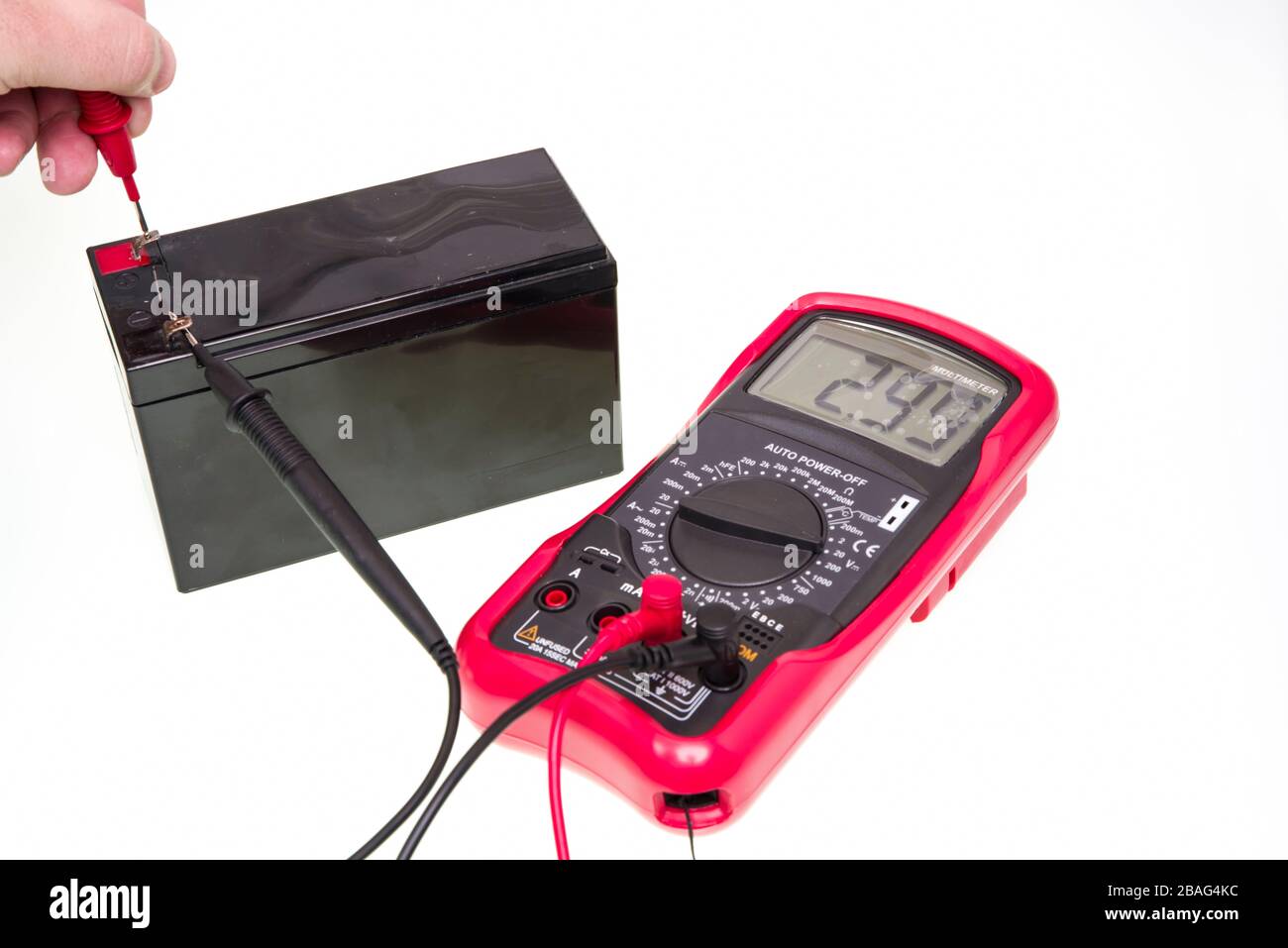 Man misurazione della tensione della batteria con strumento multimetro digitale, su sfondo bianco Foto Stock