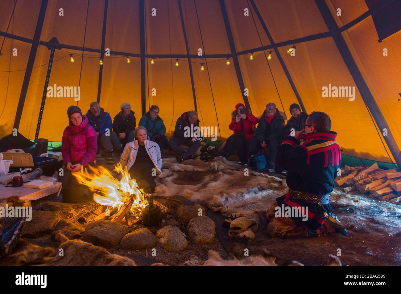 Turisti all'interno di un lavvu, una tenda che è una dimora temporanea usata dal popolo Sami qui al villaggio Sami di Rottas vicino a Kiruna in Lapponia svedese Foto Stock