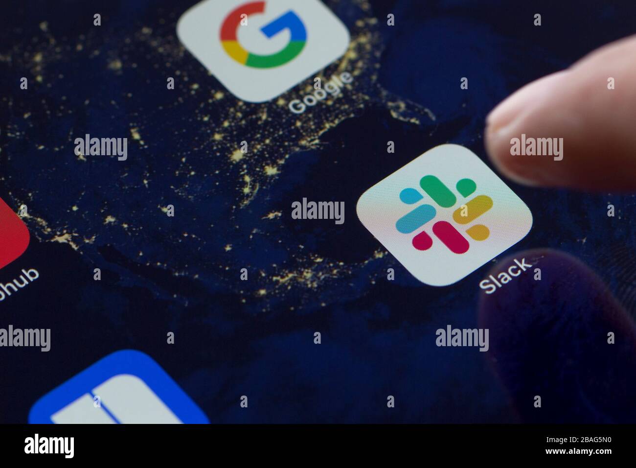Primo piano dell'icona dell'app mobile allentata su un iPad e un dito che la apre. Slack è un software B2B, un Messenger sul posto di lavoro, uno strumento di comunicazione di gruppo o una piattaforma. Foto Stock