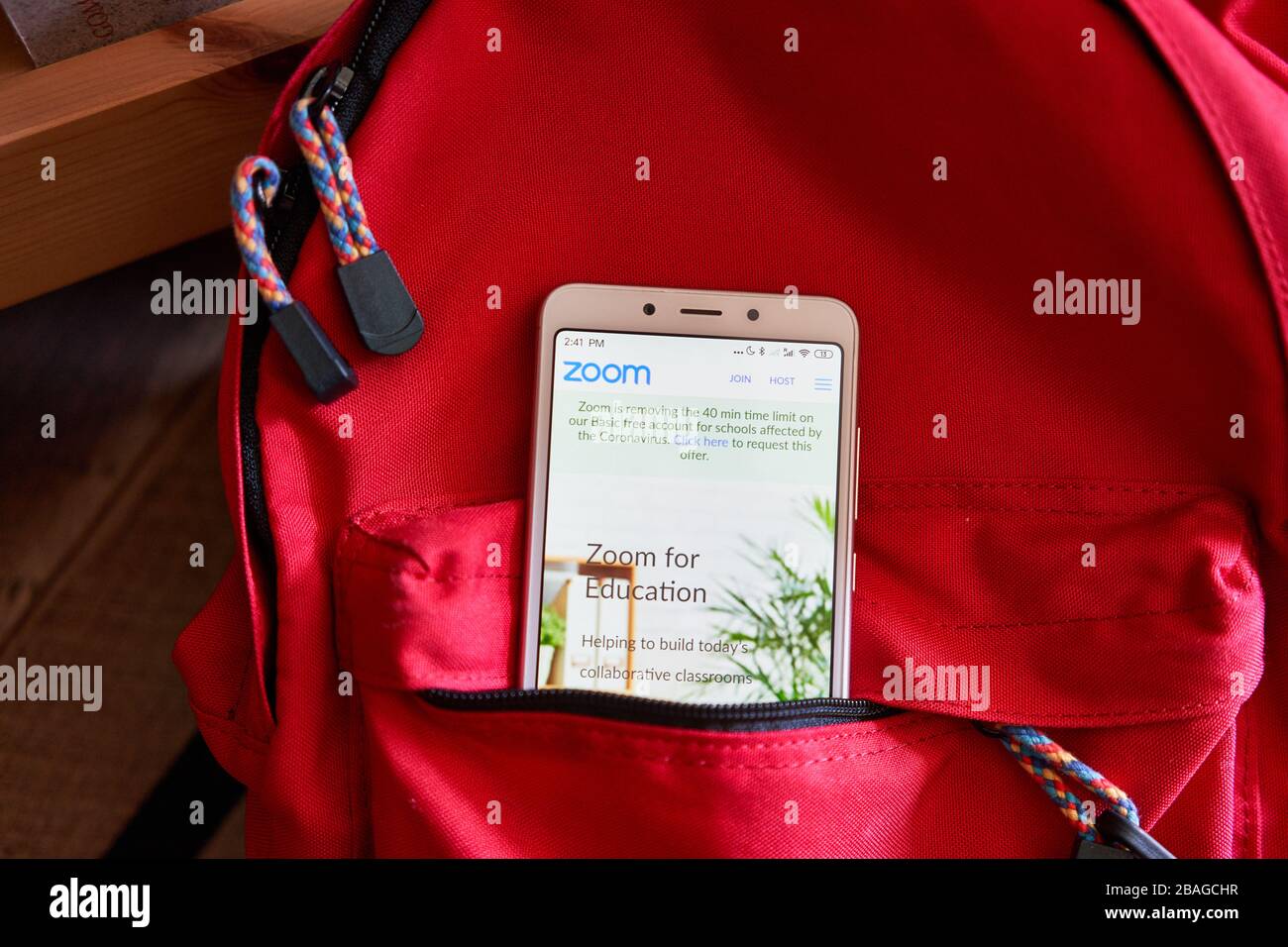 Zoom pagina web del piano didattico visualizzata su un telefono in uno zaino della scuola. Zoom offre gratuitamente alle scuole k-12 i propri strumenti di videoconferenza alla chiusura delle scuole. Foto Stock
