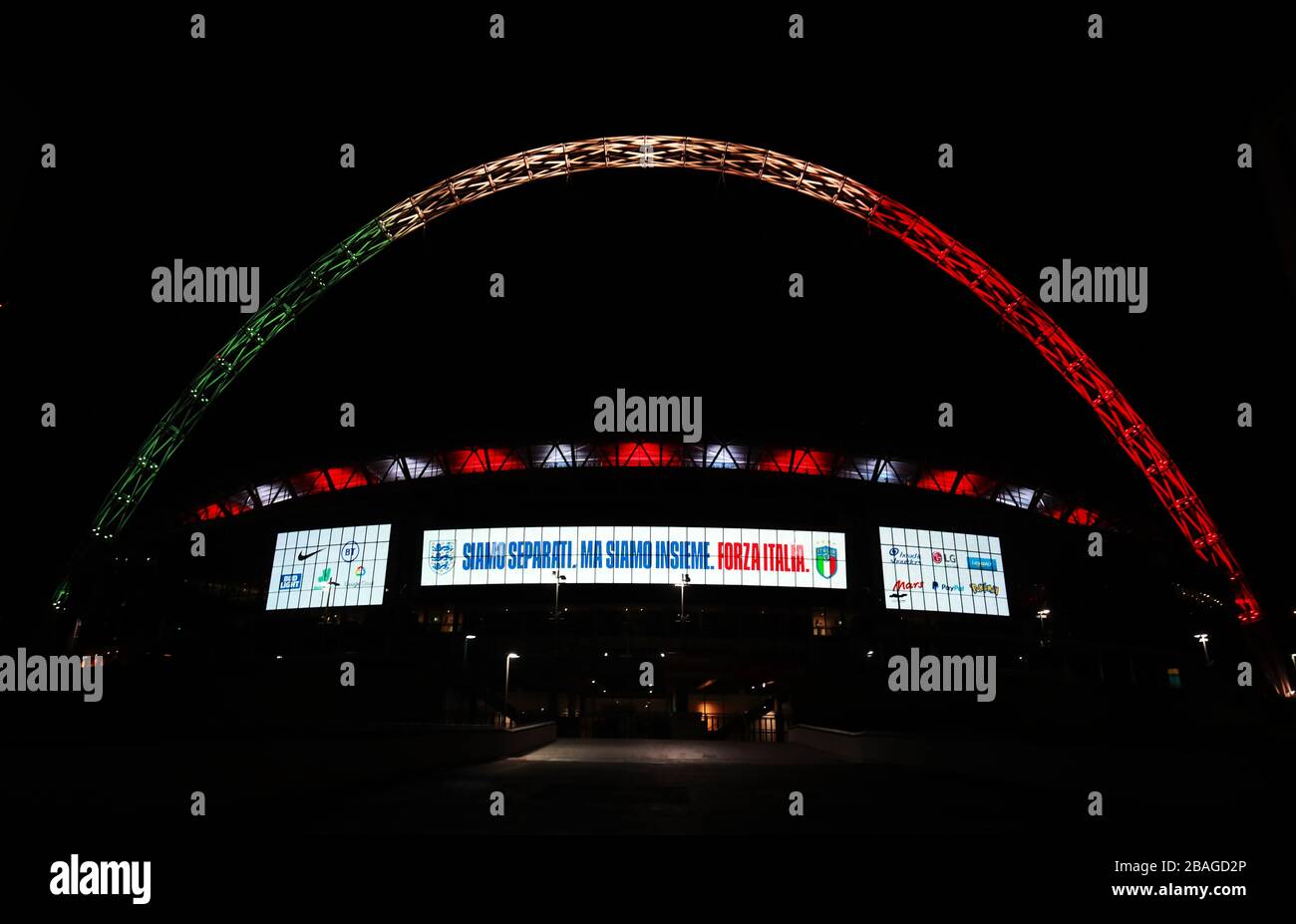 L'arco di Wembley a Londra è illuminato dai colori della bandiera italiana come gesto di solidarietà da parte della squadra di calcio inglese. Foto Stock