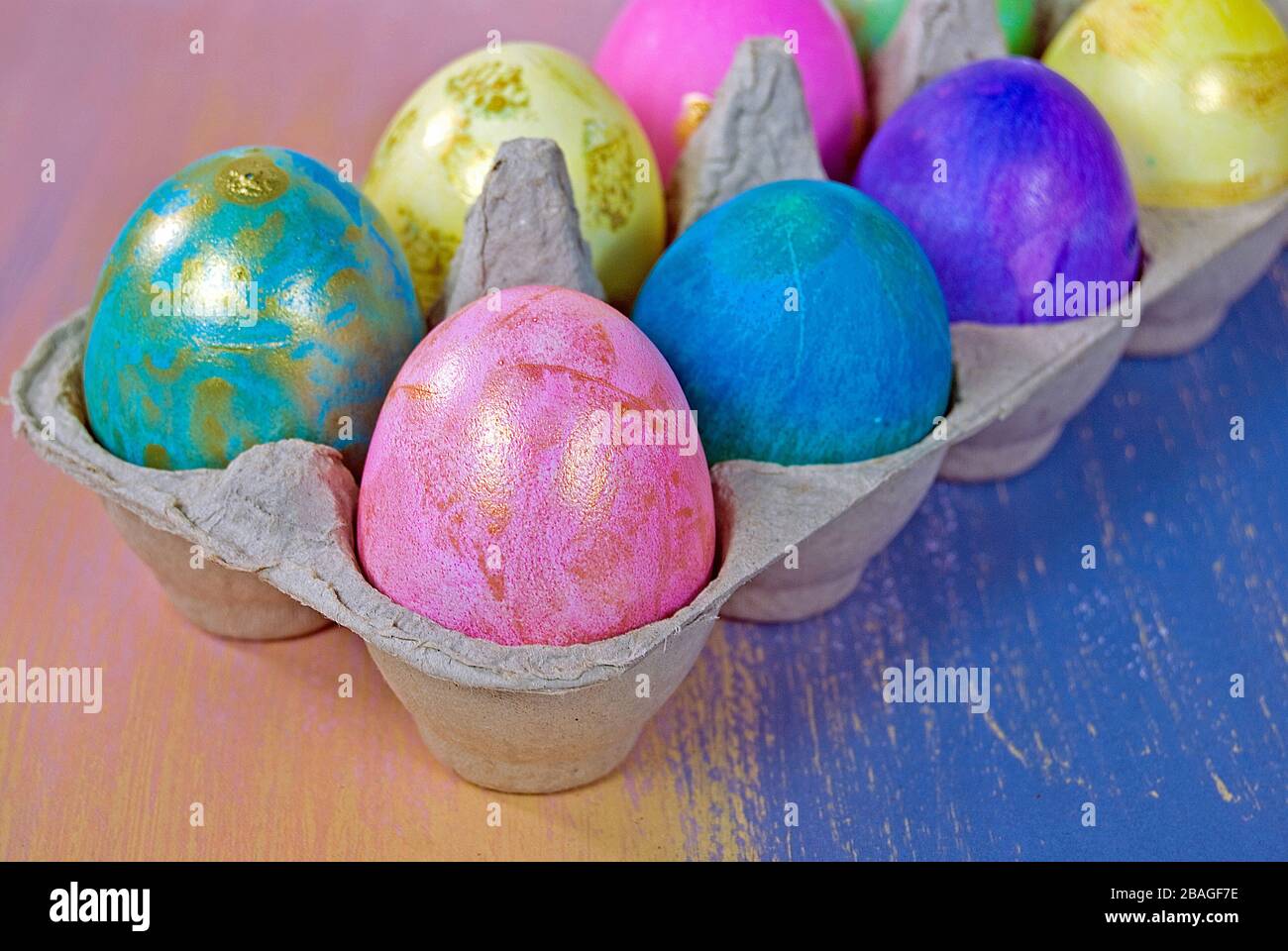 Primo piano di colorate uova di Pasqua con accento dorato in cartone grigio Foto Stock