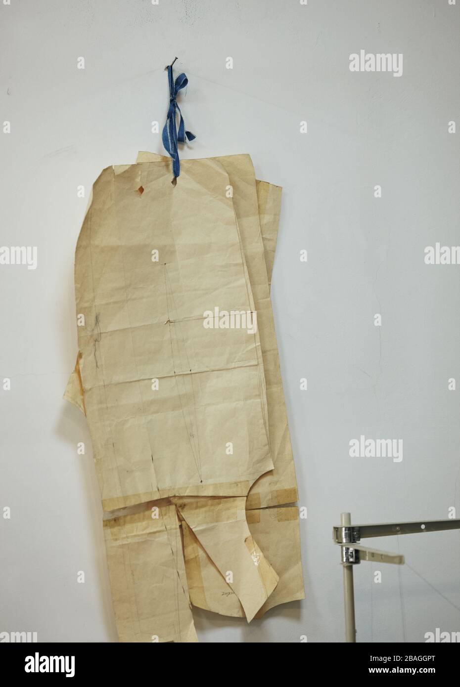 i modelli di carta per cucire i formati differenti appendono sulla parete in un interno della fabbrica di cucito. Foto Stock