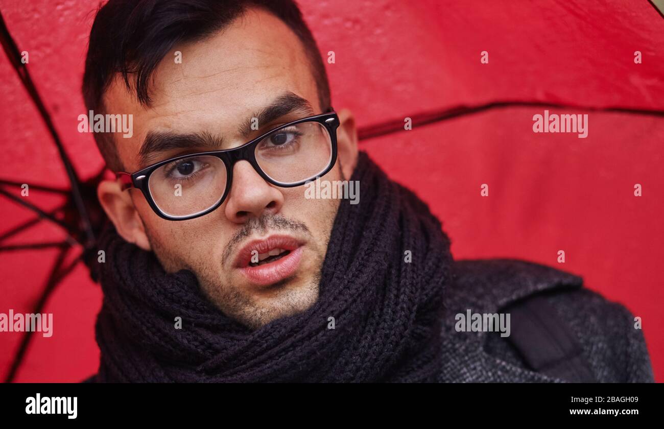 l'uomo d'affari va sotto la pioggia con ombrello rosso Foto Stock