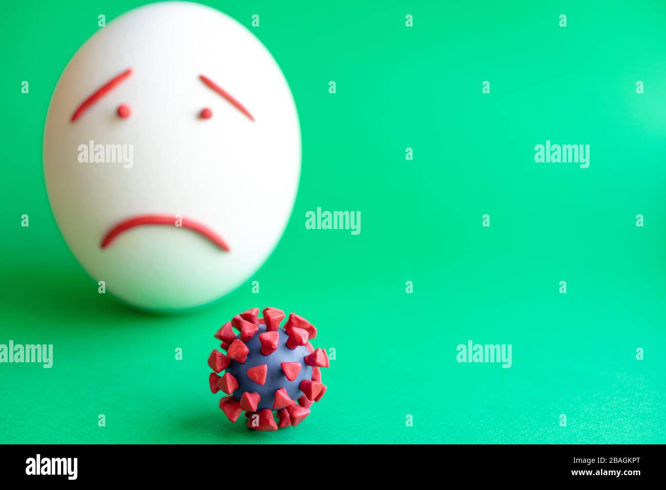 Modello di coronavirus plastificato e isolato di uovo su sfondo verde. Modello plastilina di coronavirus e uovo di pasqua raffigurante paura e tristezza Foto Stock