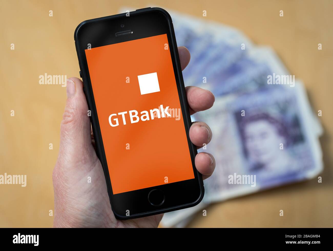 Una donna che guarda il logo Guaranty Trust Bank su un telefono cellulare. (Solo per uso editoriale) Foto Stock