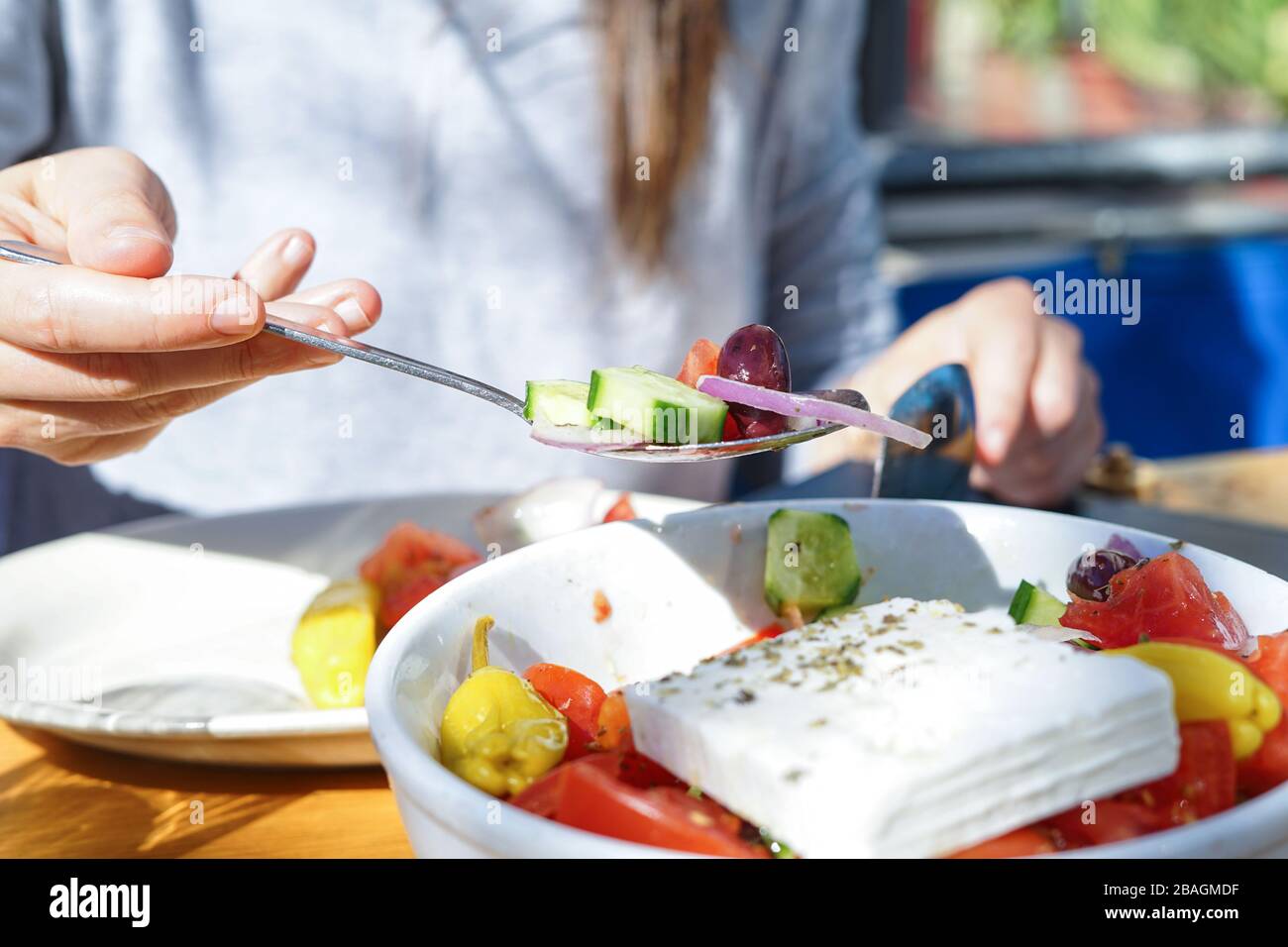 Un cucchiaio di insalata mediterranea, tenuta da una donna Foto Stock