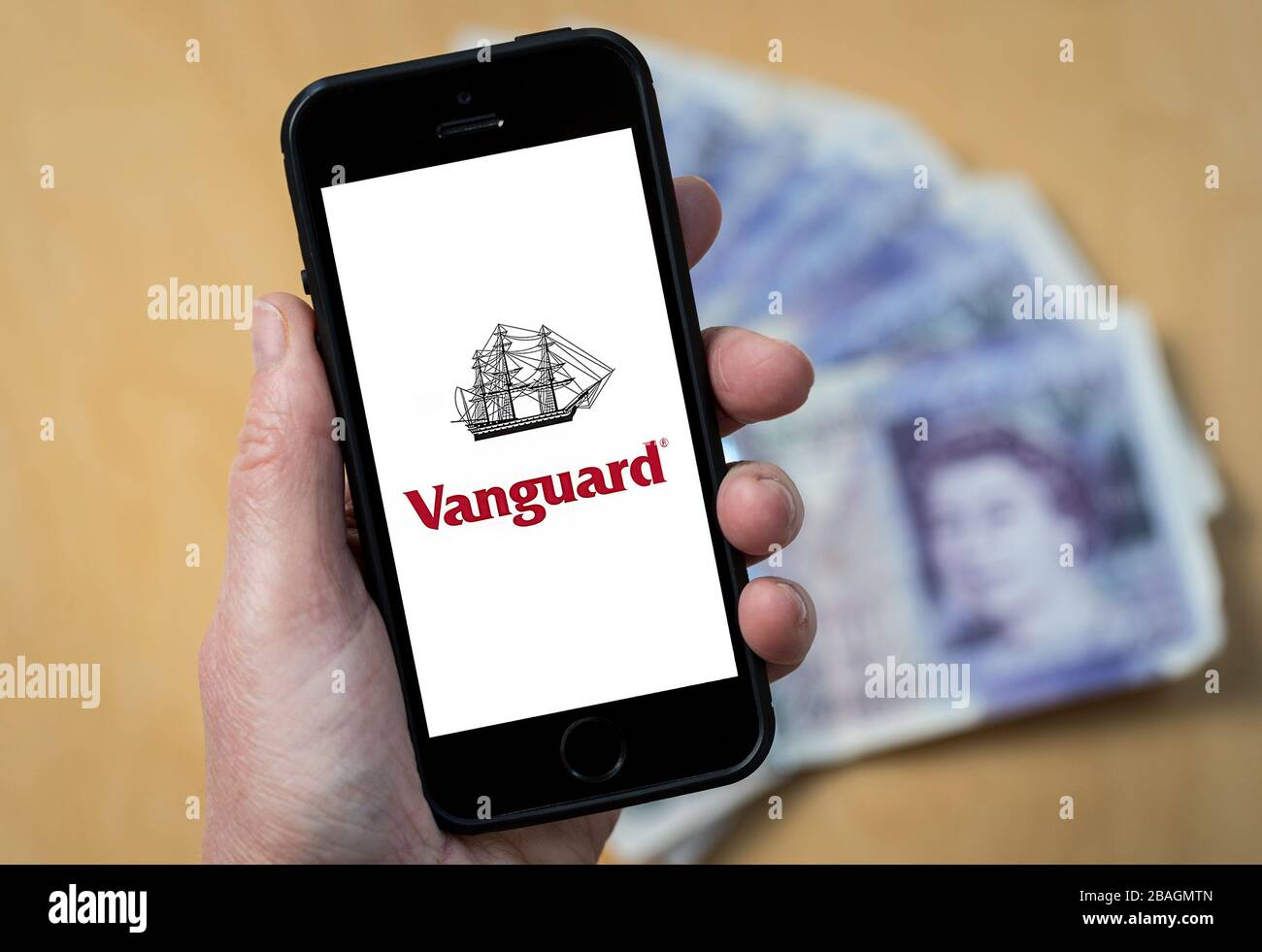 Una donna che guarda il logo Vanguard fund management Company su un telefono cellulare. (Solo per uso editoriale) Foto Stock